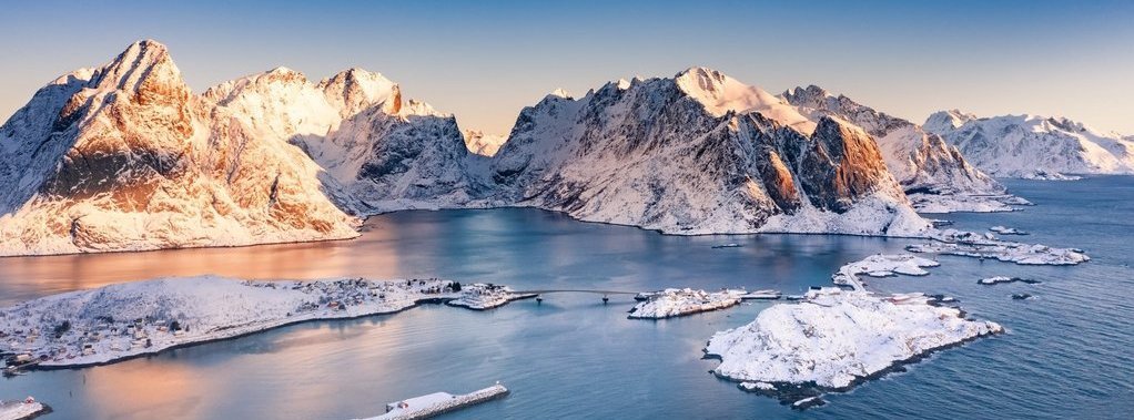 Amazing aerial view of Lofoten Islands nature from drone, winter sunrise snowy scenery of village Reine, Sakrisoy and Hamnoy during beautiful mountain ridge with alpenglow, scene over polar circle.