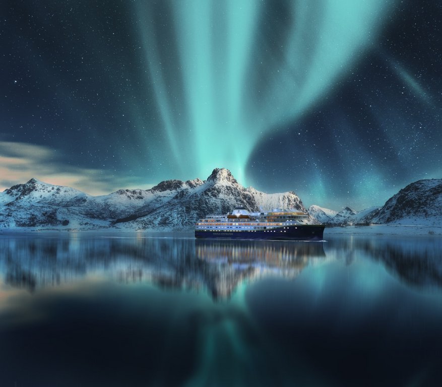 Aurora borealis over snowy mountains, frozen sea coast, reflection in water at night. Lofoten islands, Norway. Northern lights. Winter landscape with polar lights, ice in water. Starry sky with aurora